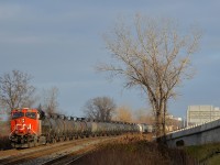<b>A lone ES44AC up front.</b> CN 377 has CN 2802 as the sole head-end unit, with CN 2812 mid-train and 185 cars in total. It is rounding a curve in Dorval as the sun comes out for a few minutes.