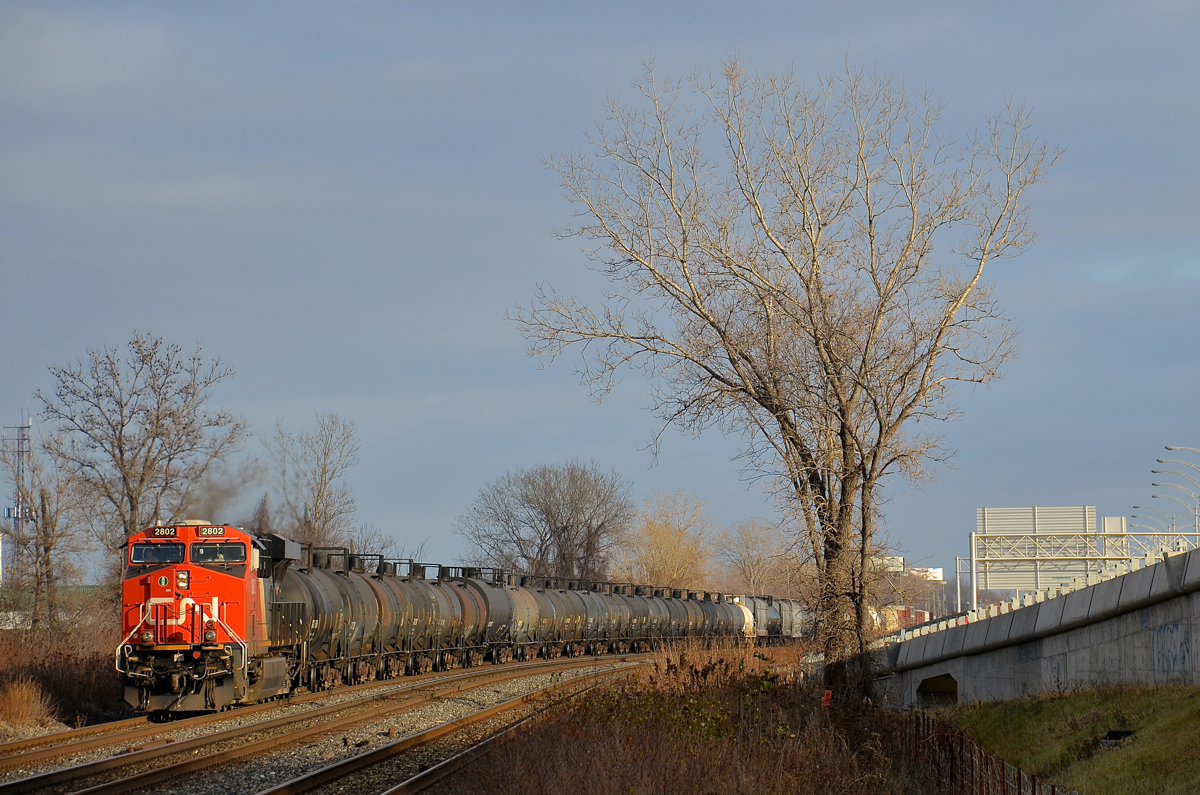 A lone ES44AC up front. CN 377 has CN 2802 as the sole head-end unit, with CN 2812 mid-train and 185 cars in total. It is rounding a curve in Dorval as the sun comes out for a few minutes.