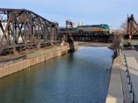 <b>A green unit over green-tinged water.</b> Green VIA 903 leads VIA 55 for Toronto over the green-tinged Lachine Canal five minutes after its 1250 departure time from Montreal's Central Station. At left is an out of use swing bridge and behind it the Wellington Tower.