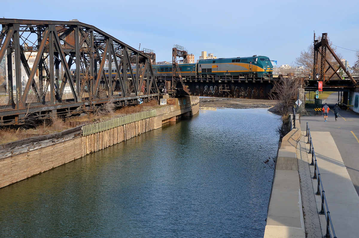 A green unit over green-tinged water. Green VIA 903 leads VIA 55 for Toronto over the green-tinged Lachine Canal five minutes after its 1250 departure time from Montreal's Central Station. At left is an out of use swing bridge and behind it the Wellington Tower.
