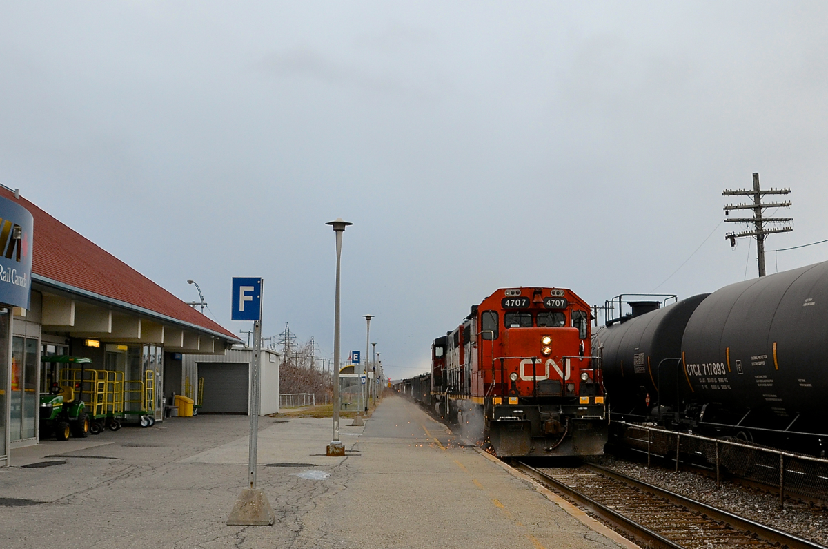 Sparks are flying. Sparks are flying as CN 586 passes through the VIA Dorval station on the south track with GP38-2 CN 4707 & GP38-2W CN 4802 for power as CN 377 passes at right on the north track.
