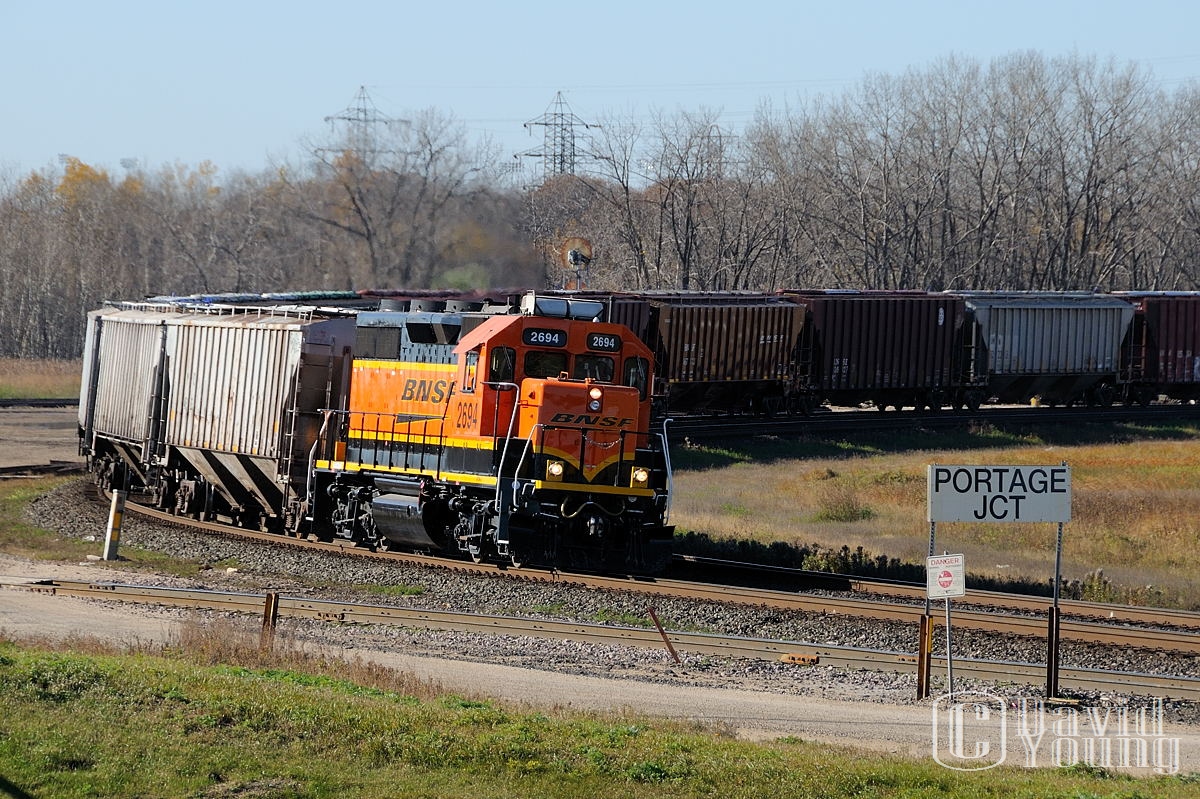 It amazes this photographer how American Class 1 railways still have small operations toiling away on isolated rails far from their own mainlines. The BNSF has one such example, and it exists within the confines of Manitoba's capital. Now known as Burlington Northern Santa Fe (Manitoba), more commonly referred to as the BNML (Burlington Northern Manitoba Ltd. -given to it after the merger between Burlington Northern and Great Northern Railroads in 1971). I know little of the operation, but they own little trackage and serve only a few customers, with their traffic being forward by CN to BNSF in Noyes, Minnesota. This day the crew in BNSF GP39-3 2694 hauls a long transfer (50ish? cars) around the curve at Portage Jct. and into CN's Fort Rouge yard. After setting off their drag, they would couple onto a dozen cars for the short return trip to home rails. I would like to hear some comments from anyone more knowledgeable about the operation.