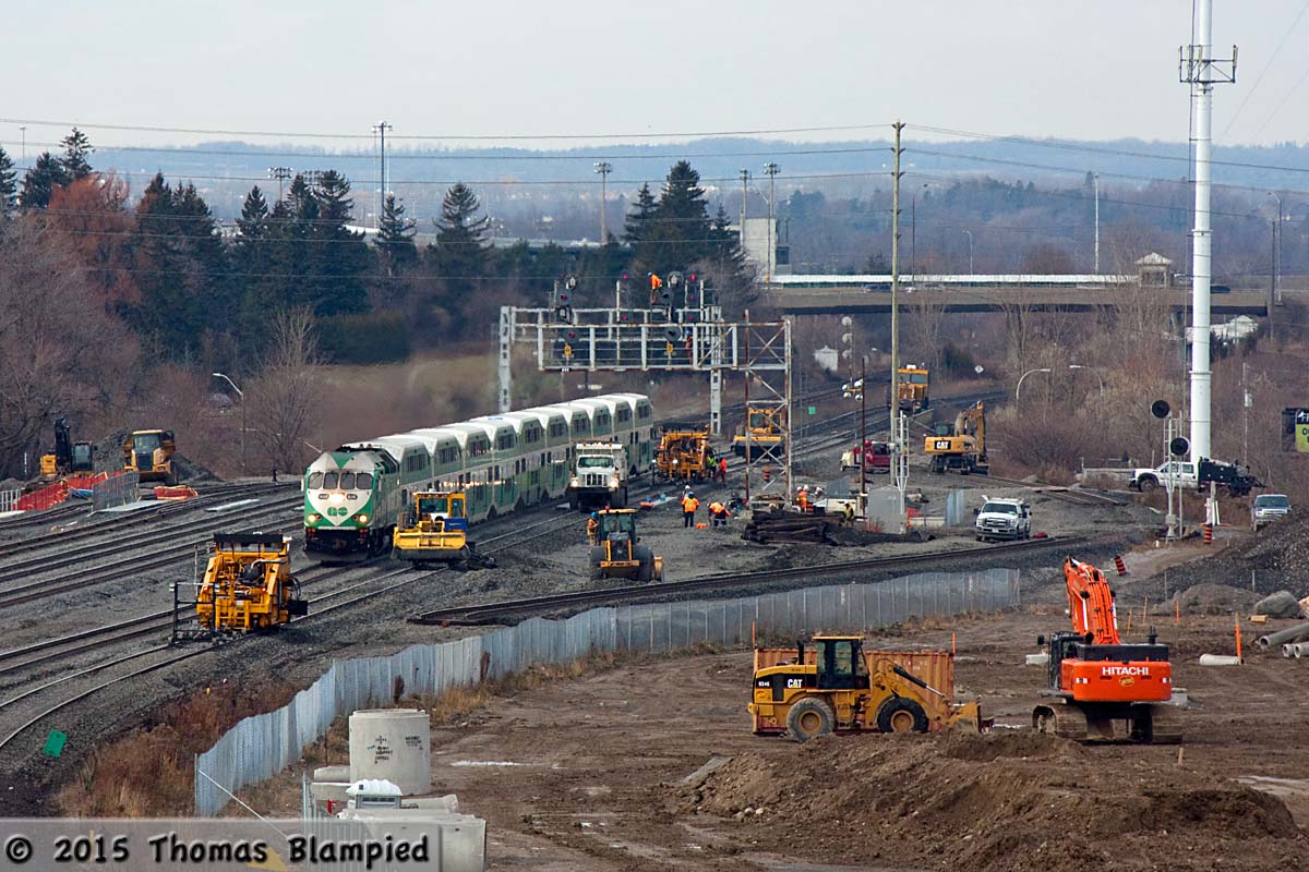 The past few weekends have seen construction on the new South Blair Street grade separation intensify. WIth the underpass largely built, crews have been busy returning the GO Sub to it normal alignment. To make construction easier, GO trains east of Pickering have been operating on an hourly schedule, allowing crews more track access. In this scene (shot from the Hopkins Street overpass, which is slated to be demolished once the South Blair underpass opens), GO 656 slowly pulls eastbound train 910 through the construction site, while a signal technician reconnects the wiring on the top of the signal bridge which was temporarily dismantled during construction.