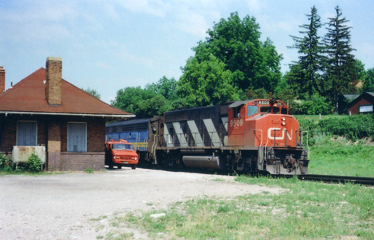 This image is "pre-VIA" as we know it.  In 1977, VIA was but an extension of CN, formed in 1976. The passenger business spun off; separate identity under the CN banner,  hence the CN leader 9509 and the trailing steam generator car already in that familiar VIA paint scheme. The national passenger system as we know it did not materialize until 1978. The old Paris station stood for a few more years, not sure when it was demolished, but it served as amaintenance storage building for quite a long while.