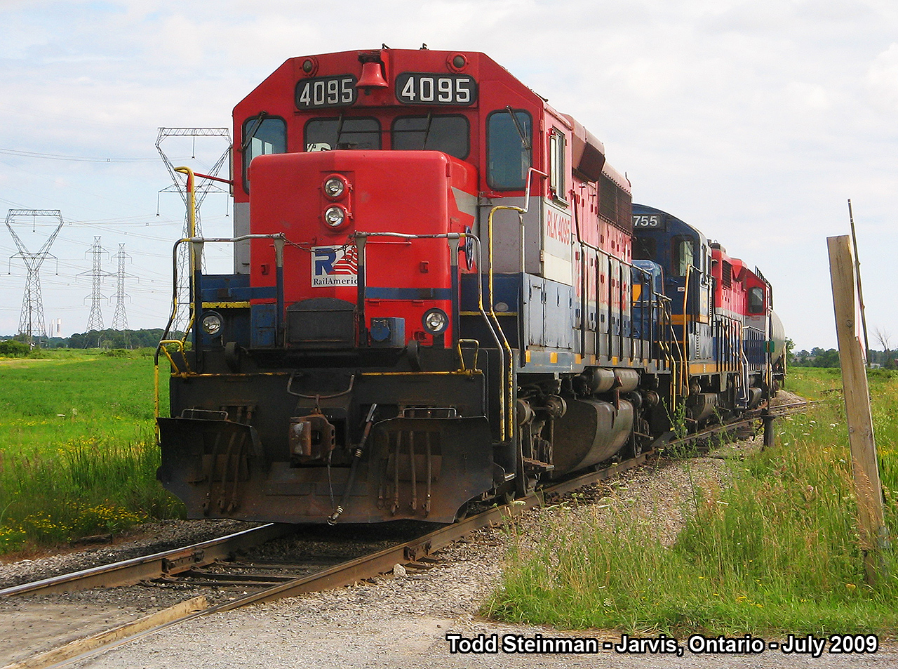 There is nothing like a country drive. On this July evening, I went to what I once considered one of my favourite spots to railfan in Haldimand County. Here, RailLink (Rail America) 4095, 1755 and an unidentifiable third engine are tied down for the night with a string of tanker cars. This became known as 'Garnet' for the railway - after the 'realignment' was built (mid 70's) to not only serve the Imperial Oil Refinery, but to the Ontario Power Generation plant in Nanticoke as well. Just off to the left remains a switch that was part of the interchange with the Air Line that ran through Jarvis, where only a spur remains today to store excess tanker cars bound to and from Imperial Oil. 
Much has changed since this photo was taken outside of Jarvis at the Concession 8 Walpole crossing. Upgrades by the Southern Ontario Railway have led to a couple of extra tracks built in the yard, as well as upgrades to their security. It was their security that asked me to leave the premises for good approx. 2 years ago, as they thought I was photographing for 'unwelcome' circumstances.