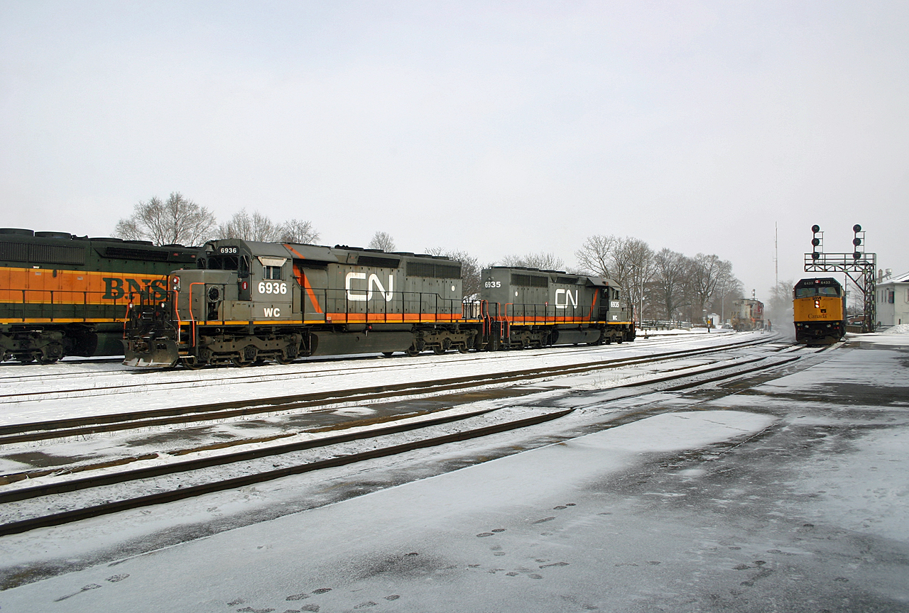 The drama began earlier in the morning when train 399 stalled on the Copetown hill after their lead unit, CN 5667 shut down, leaving the BNSF 6946 to do all the work.  550 shoved the train up the grade and they limped into Brantford to await the arrival of Q148, as 399 would be unable to make the grade out of Hardy and into Paris.  148 arrived with the intention of setting out their trailing unit, WC 6936 at Paris for 399 to lift.  Simple enough?  Well, BNSF had gotten tired of MU cables going missing and bolted the cable onto the BNSF 794; with no other MU cables at Brantford, the only option was to set out the BNSF 794 which was facing eastwards.  The 794, sporting desktop style controls, lacked the ability to lead backwards and had to be wyed at Bayview, as the 5667 was shut down with no heat and the clock ticking towards battery power running out, leaving the unit without any functionality.  Here we see the power for 148, WC 6935 and 6936 back together in the Brantford Yard, as the BNSF 794 runs down to get in a position where 399s power (seen behind the WC units) can lift it.  As this all plays out, VIA 73 cruises into Brantford behind VIA 6433.  As luck would have it, 399 would roll through Paris a few hours later, with their pristine Warbonnet leading into the setting sun.