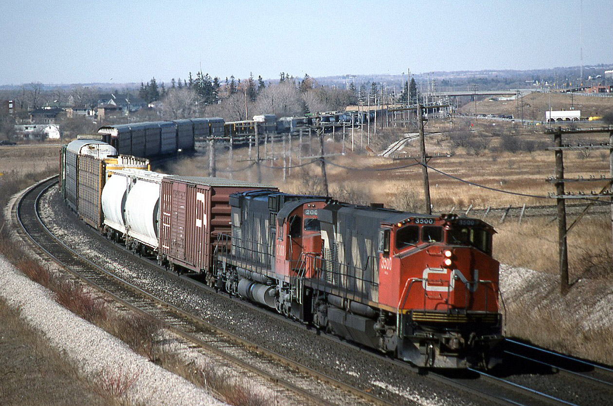 Do you recognize this location ? CN EB 318 taken from the Hopkins street overpass. March 1989. Compare this view to recently posted shots at this location. In the back ground is Victoria street, still a level crossing and the spur track to Superior propane is also viable. To the right of the two class units is what was called a pole line in them days. What a difference 26 years makes.