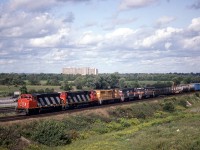 CN 9472,2031 with MEC 256, B&M 258, 263 dead in tow wb just about to duck under Durham 23 the Ajax, Whitby boarder. Destination of the last three units is unknown. Note the first two cars next to the units. A snow fence multi and a depressed flat carrying a big metal zero of some type. This location is now a total mess at this time. A new bridge for Durham 23 and a new interchange for the 412 ? to connect to the 407 extension. 
