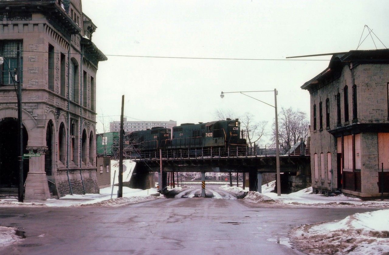 This I consider one of my bleakest scenes. What looks refreshing in this image? Nothing. Grubby old buildings, dreary pavement, dirty snow, slate blah sky, a dismal old bridge and about the unimaginative a paint scheme there ever was out there. It is a pair of old Penn Central GP 9s, now stencilled "CR" seeing the road of the future, Conrail, had been up and running almost 2 years before this photo was taken. We're at the corner of Zimmerman Av and looking down Park, toward the river; as CR 7433 and 7432 enter Canada, bringing a train over the old Steel Arch bridge. Not much has changed in all the years since this shot; the railroad is long gone but the bridge remains. Building on the left, an old bank, is still there but the other is but a vacant pile of rubble the last I checked. But that has in itself been awhile. This certainly is one dreary scene, not unlike right now as I look out the den window while typing this out and putting it to RP. :o)