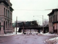 This I consider one of my bleakest scenes. What looks refreshing in this image? Nothing. Grubby old buildings, dreary pavement, dirty snow, slate blah sky, a dismal old bridge and about the unimaginative a paint scheme there ever was out there. It is a pair of old Penn Central GP 9s, now stencilled "CR" seeing the road of the future, Conrail, had been up and running almost 2 years before this photo was taken. We're at the corner of Zimmerman Av and looking down Park, toward the river; as CR 7433 and 7432 enter Canada, bringing a train over the old Steel Arch bridge. Not much has changed in all the years since this shot; the railroad is long gone but the bridge remains. Building on the left, an old bank, is still there but the other is but a vacant pile of rubble the last I checked. But that has in itself been awhile. This certainly is one dreary scene, not unlike right now as I look out the den window while typing this out and putting it to RP. :o)