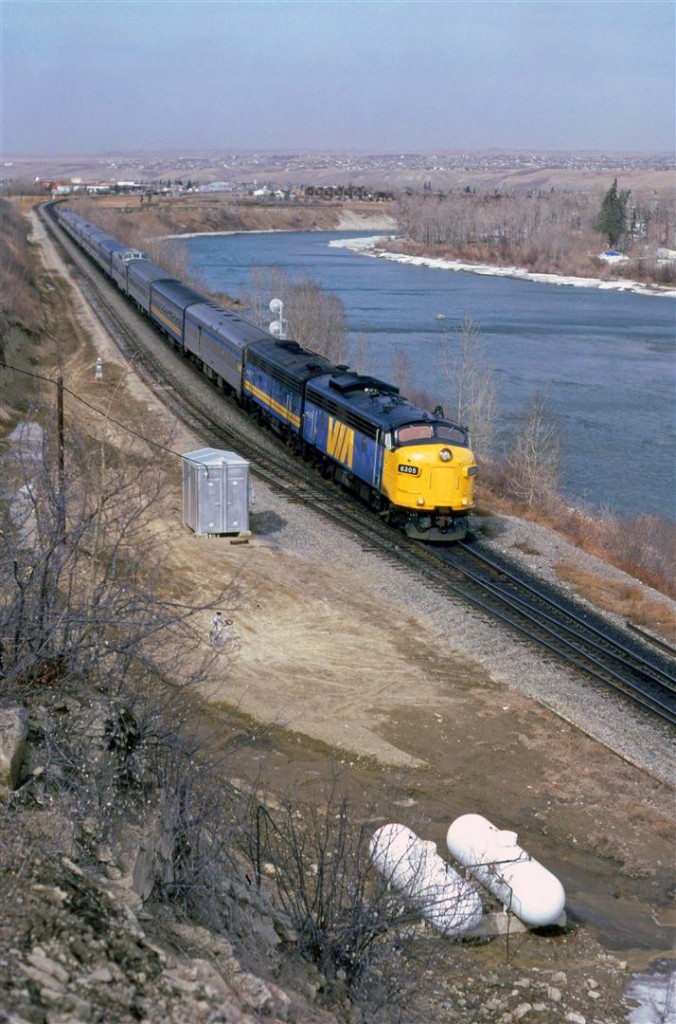 Winter's grip is loosening, at the end of March, but there is still plenty of cold to come. There is still ice on the banks of the Bow River, and buds on the trees are still over a month away. VIA's eastbound "Canadian" approaches the east switch of Brickburn Siding in west Calgary.