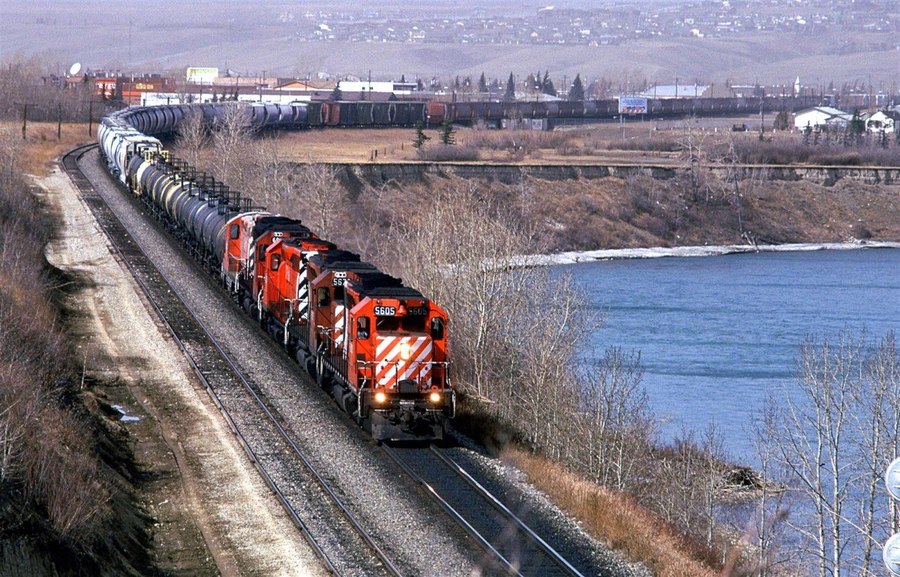 This eastbound train must have been at Kieth while the westbound "Canadian" passes, because it was only 15 minutes between the two appearances. Of note on this train, is the fifth engine. It looks to be a GP-9 and it is covered in white powder. Perhaps it was stationed at the LaFarge cement plant in Exshaw for a while.Right behind are are several tank cars used to haul molten sulphur. Although not uncommon, most sulphur out that was was solid "bits" poured into open gondolas. Behind the sulphur cars, there appear to be several cement hoppers - likely from Exshaw. Then there are box cars, likely used for wood products and finally, the train appears to be filled out with grain hoppers.