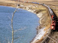 An eastbound intermodal train is on the outskirts of Calgary along the bow river (Bearpaw Reservoir). Given how many obstructions that were there in '86, I suspect that this view is not possible now.