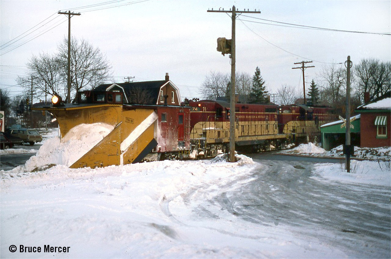 Winter of 1975-1976 just hung around like a bad apple. The powers that be finally decided it was time to dig out the plow and keep the railroad fluid. I was told this was the first time in 15 or 17 years that the plow had been activated. I had just been laid off as my position in the Brantford office on Eagle Avenue was abolished (Operator/Clerk). That is why the 2-position train order signal has a bag over it. Call time this day was around 1500 so the light is beginning to die by the time Plow Extra 74 West comes into town. I made an attempt to catch him again near Mt Pleasant but the roads were not conducive to a chase. A couple of weeks later I had secured my new job with C&O, and it would be 8 years before I set foot near TH&B property again.