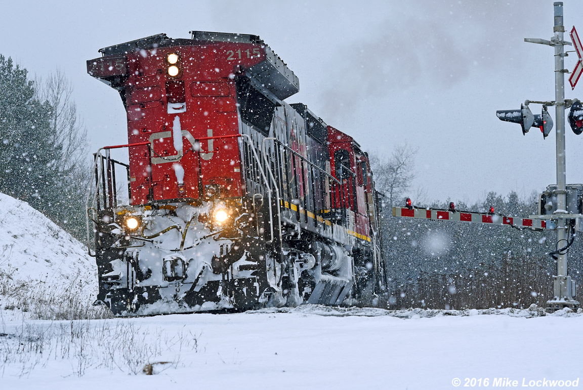 Down to about 1mph, maybe less, CN 2115 leads 318's train to the McCowan Road crossing at mile 38.38 Bala Sub. Sound somewhat muted by the snowfall, the shuddering of the wheelslip control, just letting them slip ever so little, was easier to discern. The hogger was a good sport, who stoically embodied the 'I think I can' spirit of the moment. I took 13 minutes to move roughly 1.2 miles to the Davis Drive overpass, where the pace had noticeably improved. One of those moments that helps you remember why railroading is fascinating... the drama can be quite compelling (and no GEVO's). 1405hrs.
