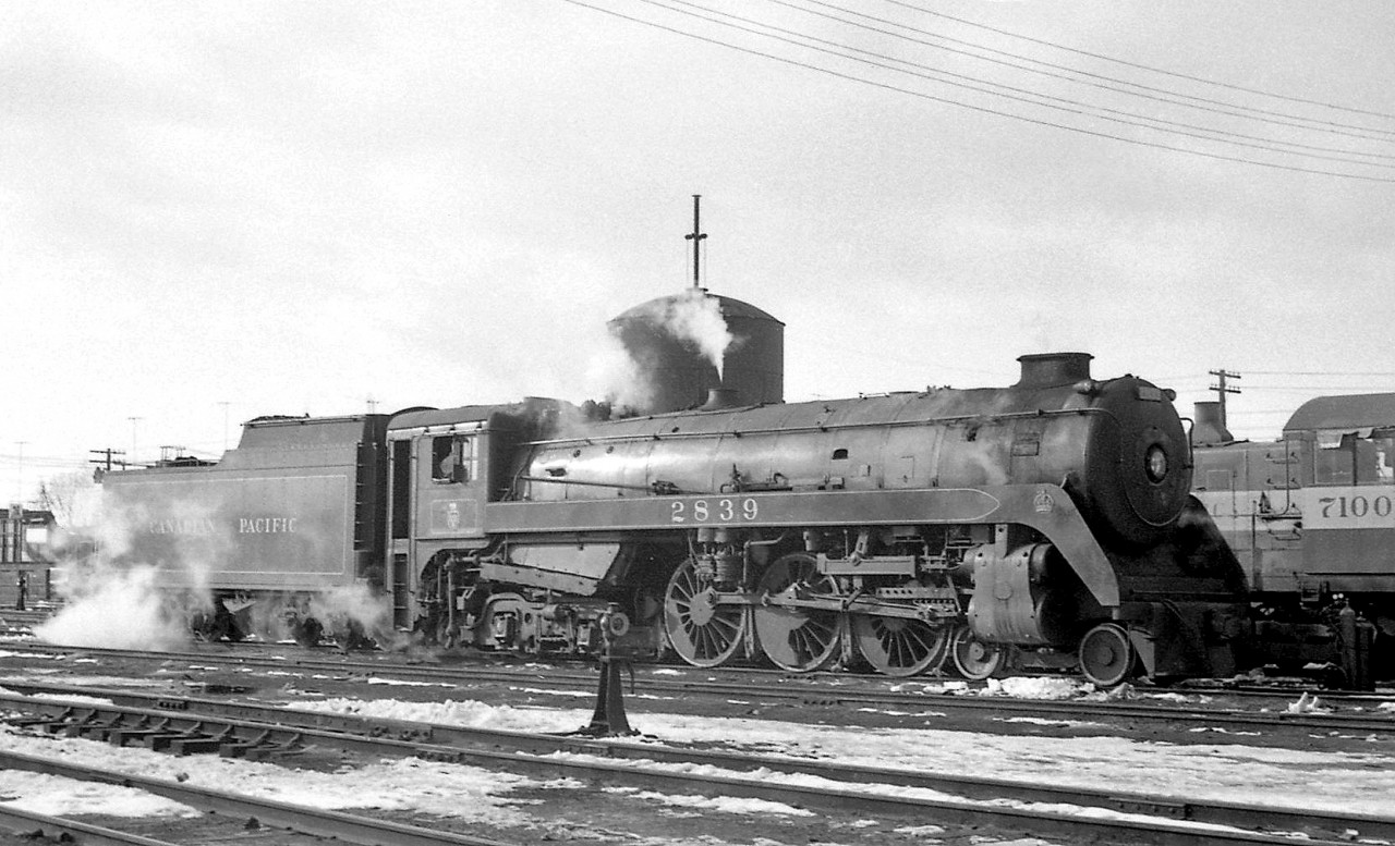 Another view of Canadian Pacific 4-6-4 "Royal Hudson" 2839 in front of the water tower at Lambton Yard in February of 1960, near the end of the steam era, after serving as a pusher on a freight to Orr's Lake. By then, CP had run an "offical" last steam train out of Toronto, but steam did survive for a few months after in remote terminals like Port McNicoll, or as helpers. The cab of MLW S4 7100 is visible to the right, one of a handful of diesel switcher units assigned Lambton Yard for yard switching and local duties.  Another view of CPR 2839 at Lambton on the same day: http://www.railpictures.ca/?attachment_id=22158 CPR 3722 during the last weeks of steam at Port McNicoll ON: http://www.railpictures.ca/?attachment_id=22492 Steam mingling with diesel at Galt Station in 1958: http://www.railpictures.ca/?attachment_id=22003