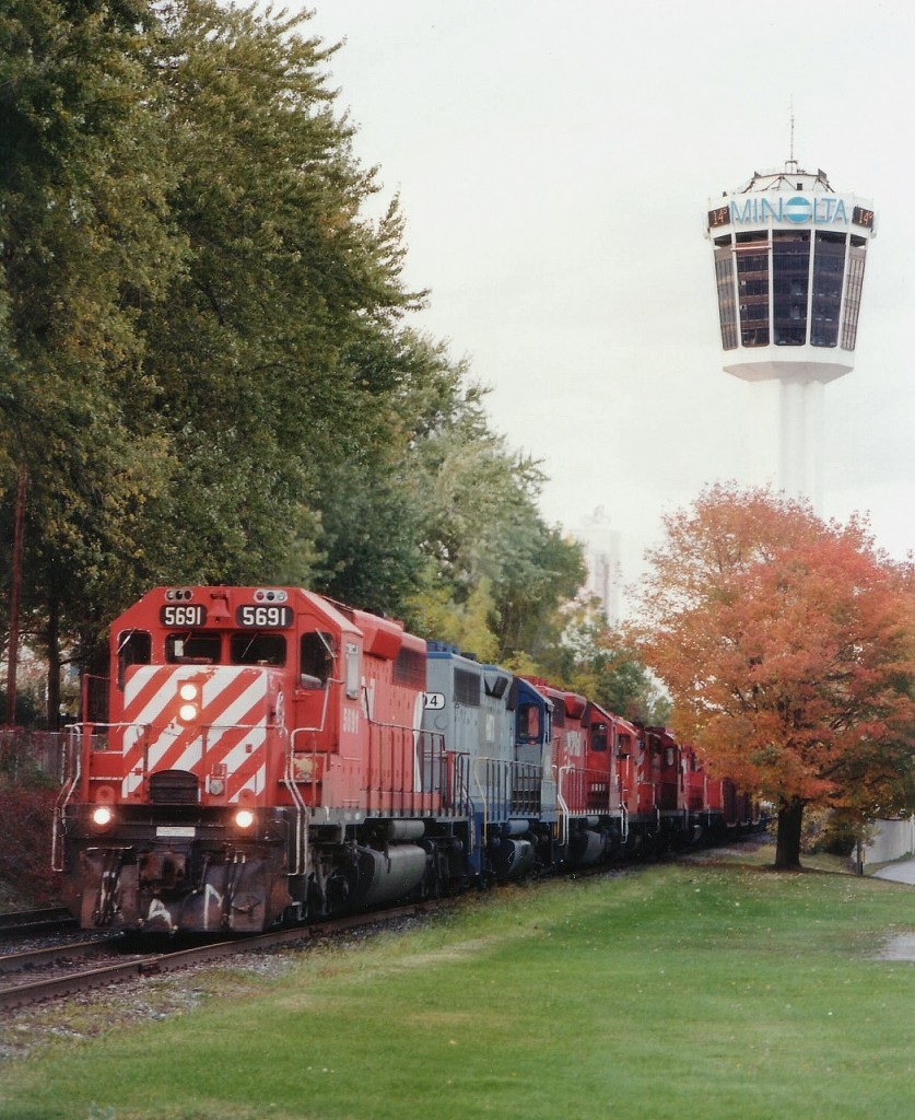 This rather huge train has just made its way thru Niagara Falls tourist area, tying up the traffic and p***ing off the Clifton Hill regulars as it slowly moved along toward Montrose Yard. This train was exceptionally long; I wish I had the car count, but just the power up front was impressive......CP 5691, HATX 404, CP 5639, 8228, 1807, 5519 and 1859. The train is seen approaching the South Siding Switch (Chippawa Spur. The line to the Spur from Brookfield is still in place and active these days, but all track north and east of this location has been removed.