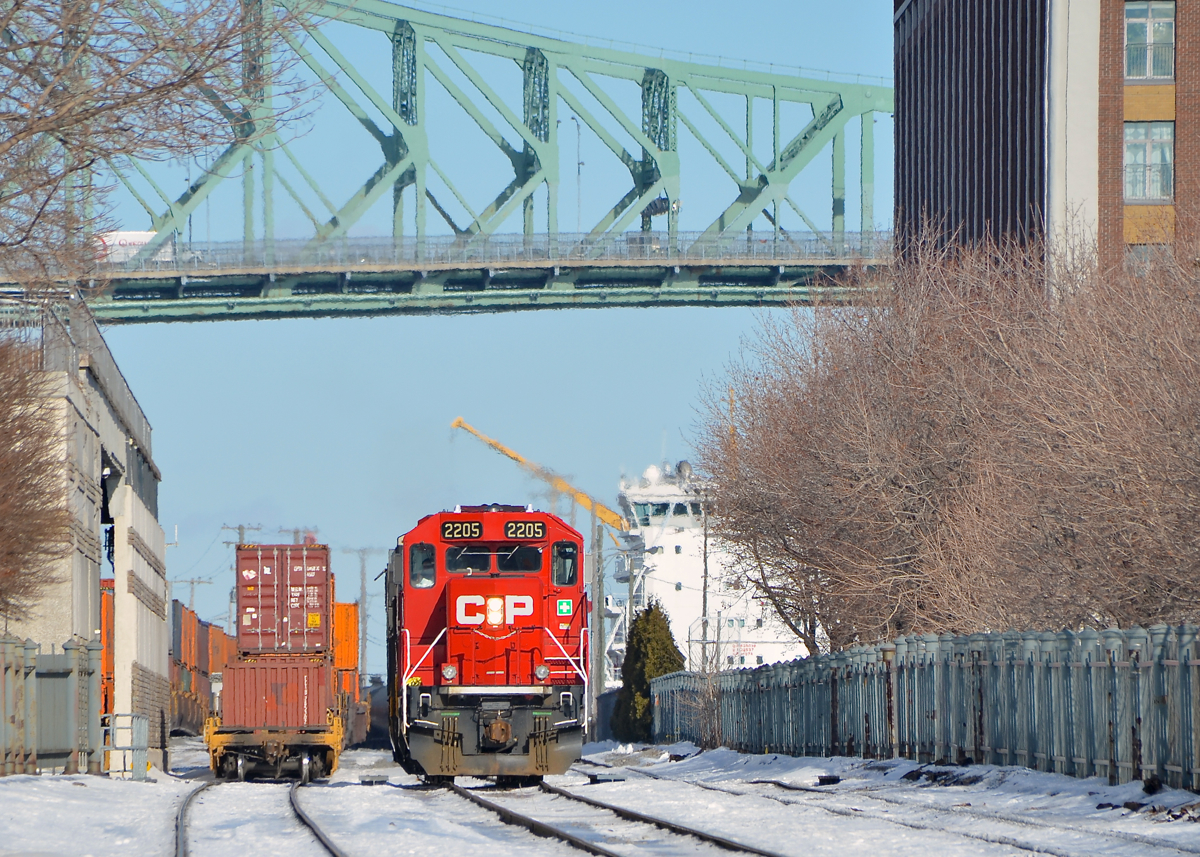 Trains and a ship. CP 142 with an unusual GP20C-ECO leader and two NS units trailing (CP 2205, NS 8362 & NS 2693) is light power in the Port of Montreal after dropping off its train. It is backing up light on its way to St-Luc Yard. At right is a ship berthed in the port.