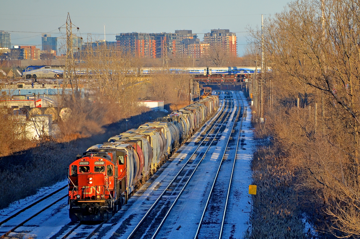 EMD's below and above. In the foreground at ground level, CN 500 with empty grain cars from the Port of Montreal is bound for Taschereau Yard with EMD's CN 7062 & CN 4808 on CN's Montreal sub. Up above on CP's Adirondack sub, AMT 75 is being pushed by an unidentified F59PHI, on its way to its next stop at Lasalle Station.