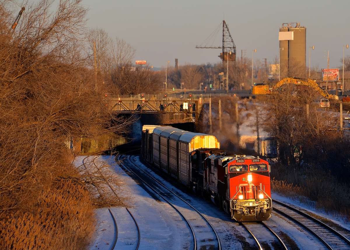 Under a soon to be demolished tunnel. CN 401 is exiting from a tunnel that will be demolished shortly as part of infrastructure projects in the area with CN 2909 leading. It's about 25 minutes before sunset and the lead unit is bathed in some great winter light.