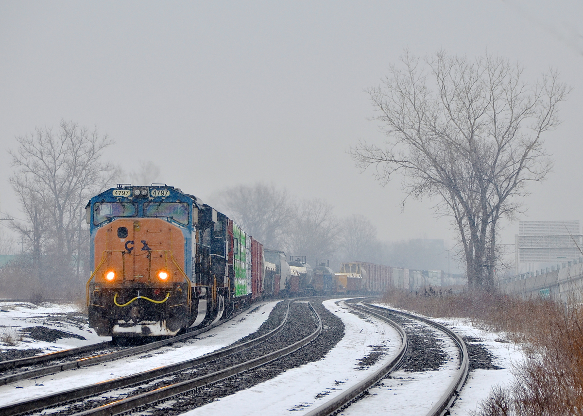 Faded CSX lettering in the snow. With light snow falling, SD70MAC CSXT 4797 with faded CSX lettering on the nose leads CN 327 through Dorval.