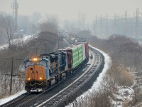 <b>CN 327 around a curve.</b> With light snow falling, SD70MAC CSXT 4797 with faded CSX lettering on the nose leads CN 327 around a curve in Beaconsfield. Trailing are CSXT 5520 and CN 4107.