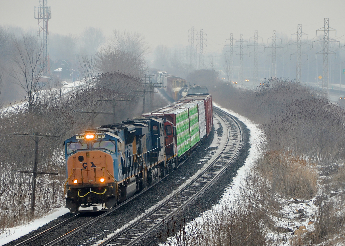 CN 327 around a curve. With light snow falling, SD70MAC CSXT 4797 with faded CSX lettering on the nose leads CN 327 around a curve in Beaconsfield. Trailing are CSXT 5520 and CN 4107.