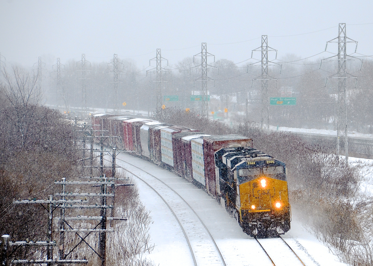 CN 327 around the corner. A pair of Boxcar logo ES44AH's (CSXT 3144 & CSXT 3002) lead CN 327 through Beaconsfield on a snowy afternoon with 69 cars in tow.