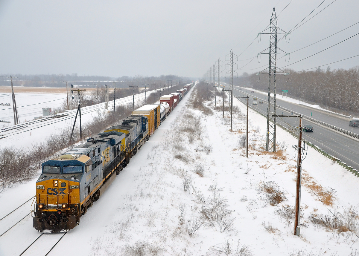 A short CN 327 in the snow. CSXT 5246 & CSXT 551 lead a short CN 327 through Ste-Anne-de-Bellevue. After waiting for two VIA Rail trains to clear, they have crossed over from the north to the south track and are bound for Coteau where they will set off cars.
