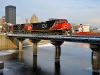 <b>Trains and boats in the port.</b> CN 149 is crossing the Lachine canal as it leaves the Port of Montreal with CN 2578, CN 8941 & CN 2299 for power. It is passing the bulk carrier <i>Baie St-Paul</i>, laying over in the port for the winter. Barely visible behind it is another boat, the <i>Algoma Navigator</i>.