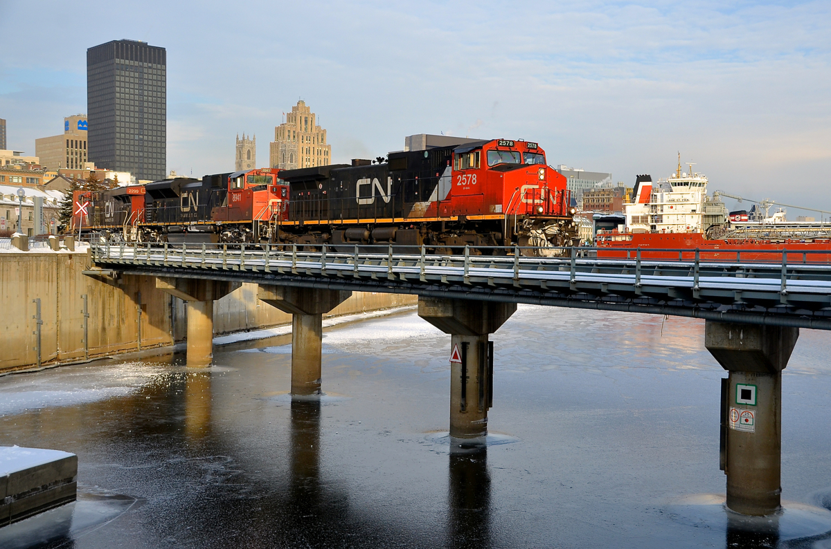 Trains and boats in the port. CN 149 is crossing the Lachine canal as it leaves the Port of Montreal with CN 2578, CN 8941 & CN 2299 for power. It is passing the bulk carrier Baie St-Paul, laying over in the port for the winter. Barely visible behind it is another boat, the Algoma Navigator.