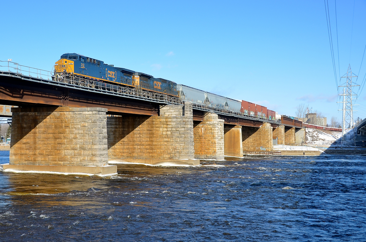 A clean repaint leading. Repainted AC4400CW CSXT 312 is leading CN 327 over the Ottawa River as it leaves the island of Montreal. Trailing is C40-8 CSXT 7619.