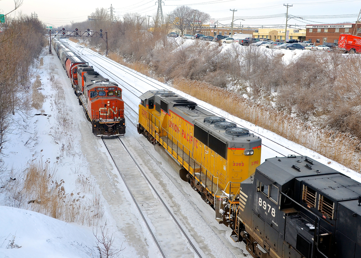CN/UP EMD meet. A rare for Montreal UP SD60M which has had the UP wings added to its nose (UP 2392, ex-UP 6237) is leading CN 529 as it approaches its terminus of Taschereau Yard. It has just started to pull after waiting for its signal for five minutes or so. Leaving the yard is CN 500 with grain loads for the Port of Montreal, with GP38-2W CN 4802 and a GP9 for power.