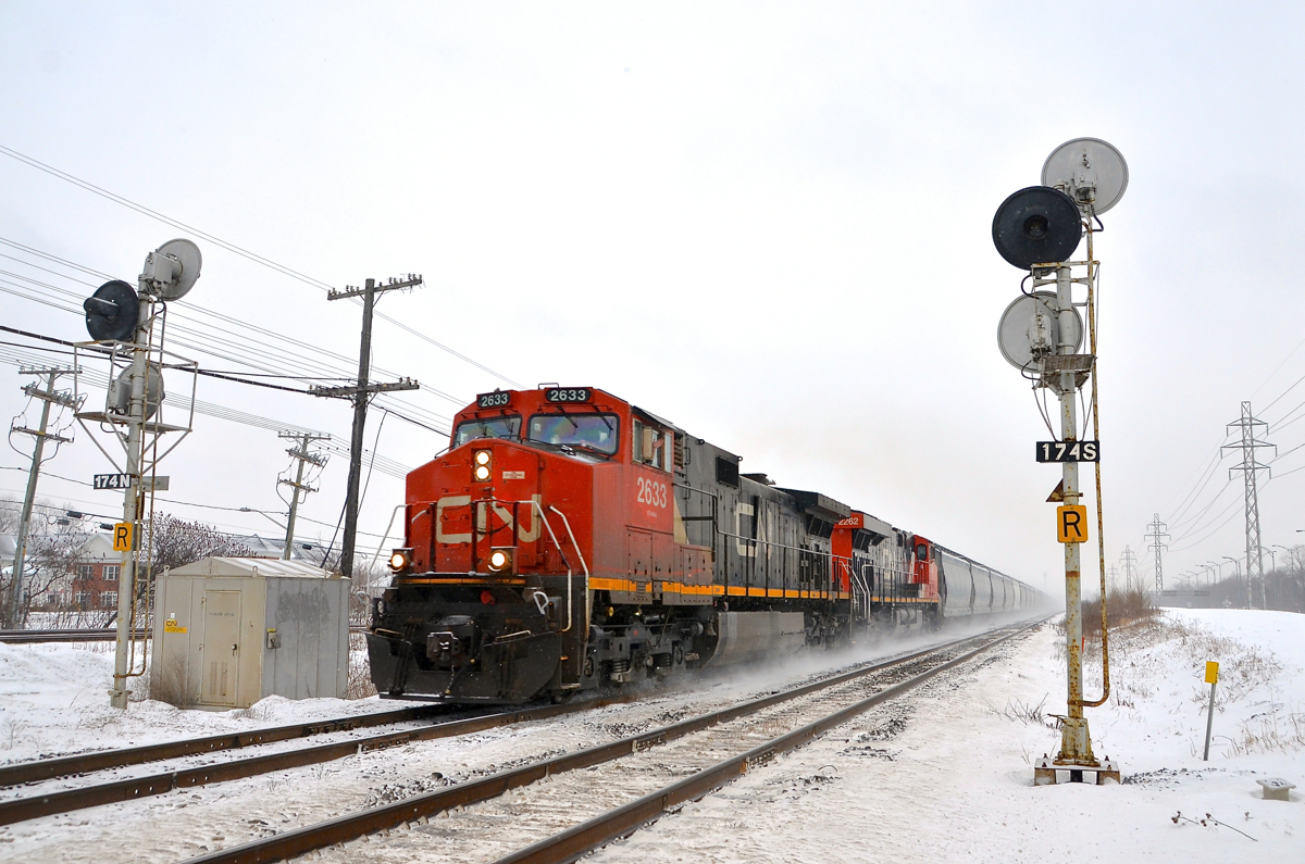 A friendly wave from the conductor. CN 377 kicks up the snow as it speeds through Beaconsfield with CN 2633 & CN 2262 for power, as the conductor waves.