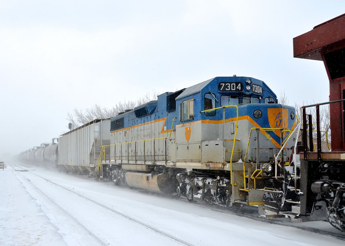 DH 7304 (one of only two lightning striped GP38-2's remaining) is through Lasalle station, trailing CP 8735 on CP 253. Presumably it is going to St-Luc for servicing.