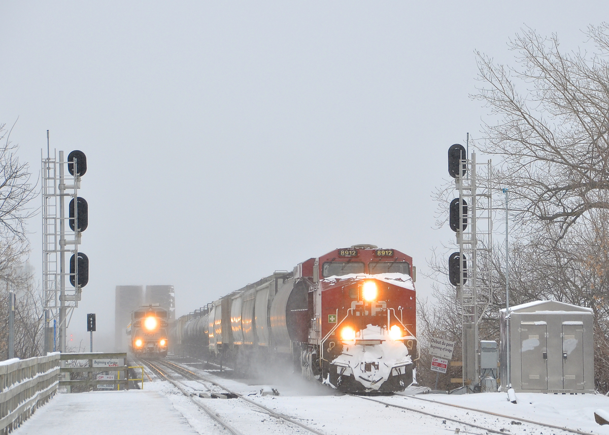 CP wins the race over the river. CP 253 with snow-covered CP 8912 as sole power has won the race to the island of Montreal as it crosses the St-Lawrence river, with AMT 74 at left not too far behind with F59PH AMT 1342 as power on a windy and frigid morning.