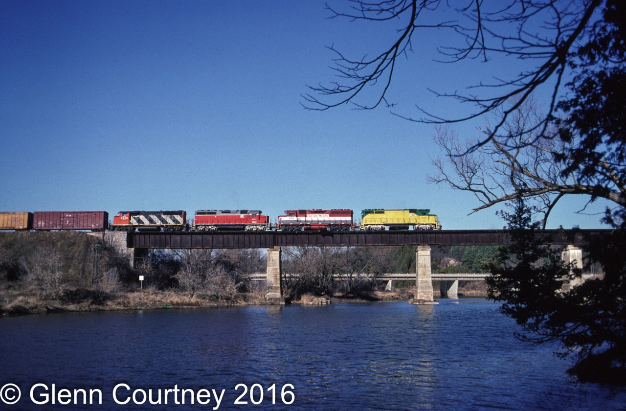 A multi-coloured locomotive consist leads GEXR 432 across the Grand River from Kitchener to Breslau enroute to MacMillan Yard.