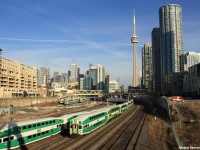 With the Toronto skyline, including the world-famous Canadian National Tower in the background, a westbound GO Transit commuter train heading towards Hamilton exits on this sunny Monday evening, among the other commuter train rush. 