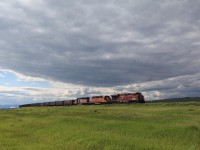 In the evening of June 13, 2015 heavy clouds from the north had eventually moved into the area of Fort MacLeod. 8819, 5717, and 5560 had a ballast train, probably from the quarry west of Cranbrook, BC in tow as they were skirting the edges of these clouds near Pincher Station for a short while.