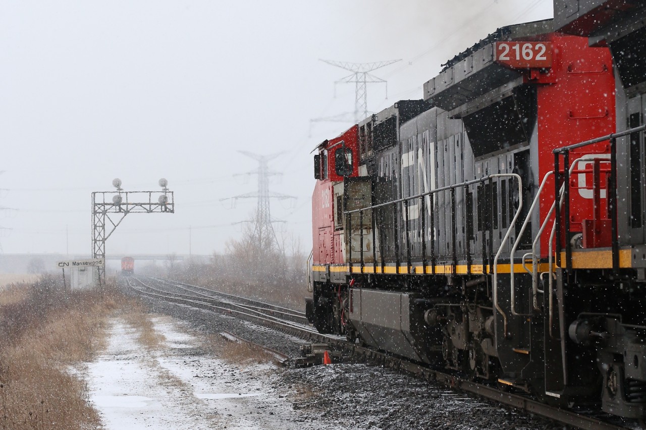 Heavy snow flurries are rolling through Milton as CN train 398 takes the siding at Mansewood. Train 435 has been given the highball and it won't be long before 398 is back on the move again and Toronto bound.