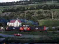 The engineer of NF210 # 919 opens the throttle of Terra Transport Extra 919 West at the Symes Bridge grade crossing in St. John's just before sunset on the evening of July 7, 1988. Built in 1956 by GMD of London, ON, this unit was one of an order of 26 diesels delivered from Montreal to St. John's on the MV Christian Smith to forever banish the Mikado and Pacific steam engines still operating on the narrow gauge line. With less than three full months of operation remaining, the sights and sounds of trains running through the scenic Waterford Valley would end for good on September 30 and the former Newfoundland Railway would be nothing more than a memory. 