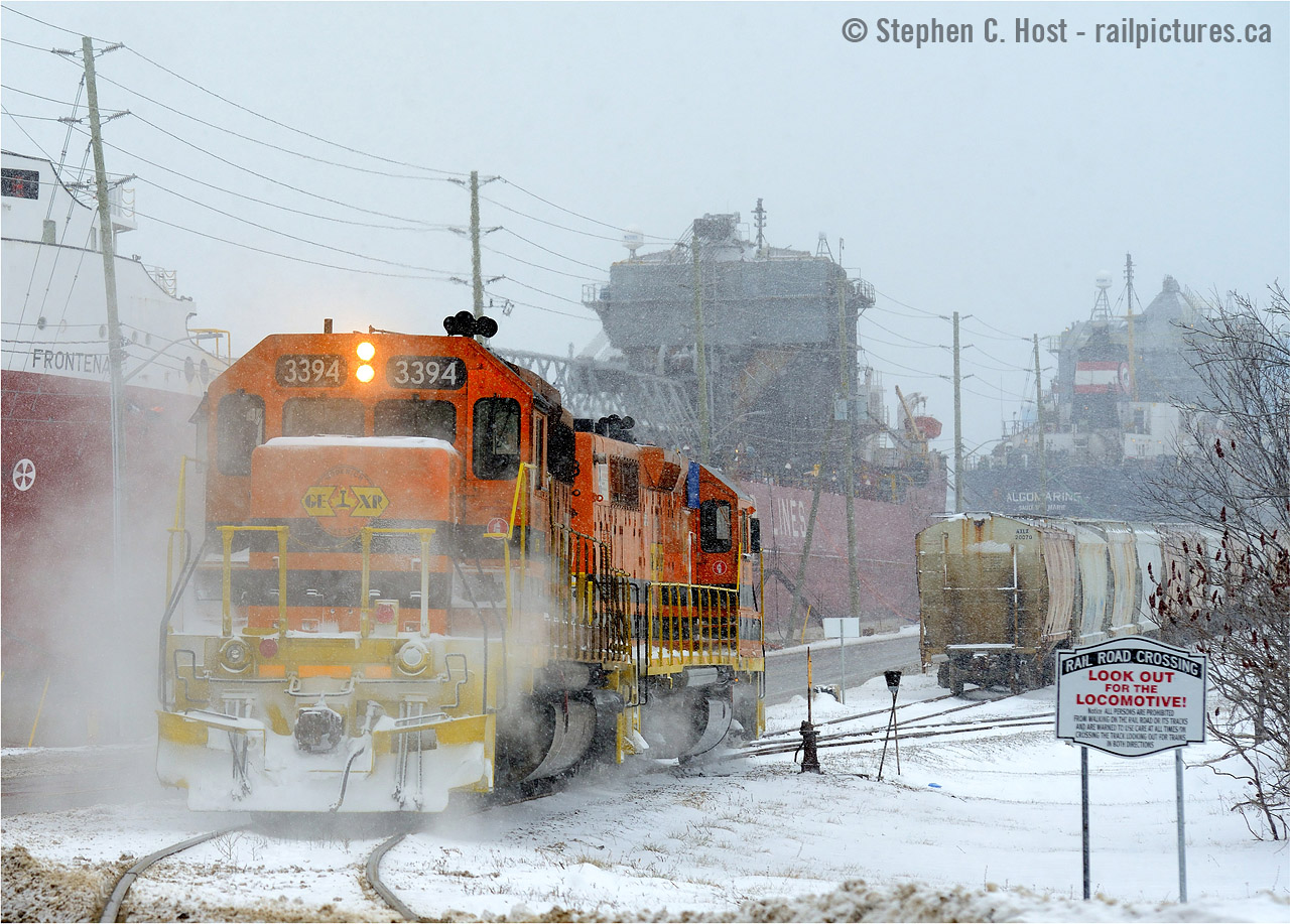 Watch out for the Smoking Locomotive The sign at right should say. SD40-2 3394 is lost in a puff of brakeshoe smoke following the 4% downward grade from the Goderich Station to port. In the background are a couple dozen loaded Salt cars waiting to climb 130 vertical feet to the station, and onward to Stratford. The motive power and crew could only muster 5 cars up the hill after numerous attempts, starting with 13 loads. Also seen are two ships, the Federal "Frontenac" and Algoma Central "Algomarine", Goderich truly is one active port of call for all modes of transport.