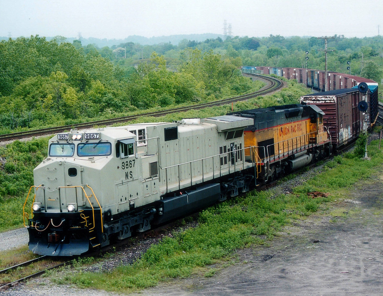 The Talbotville-Buffalo autoparts train that used to feature out-of-the-ordinary power so frequently had something a little different this day. A "Stealth" NS unit 9867 leading UP 8605. The unpainted version of the Dash-9 was not all that uncommon.As fast as GE was pumping them out, NS was pressing them into service. As this image indicates, even before they got painted. This train and its' counterpart, #327, were discontinued at the end of 2006.