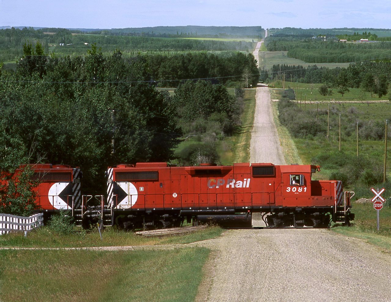 CP's Homeglen wayfreight servicing a gas plant in the rolling hills northwest of Red Deer, crosses a rural grid road