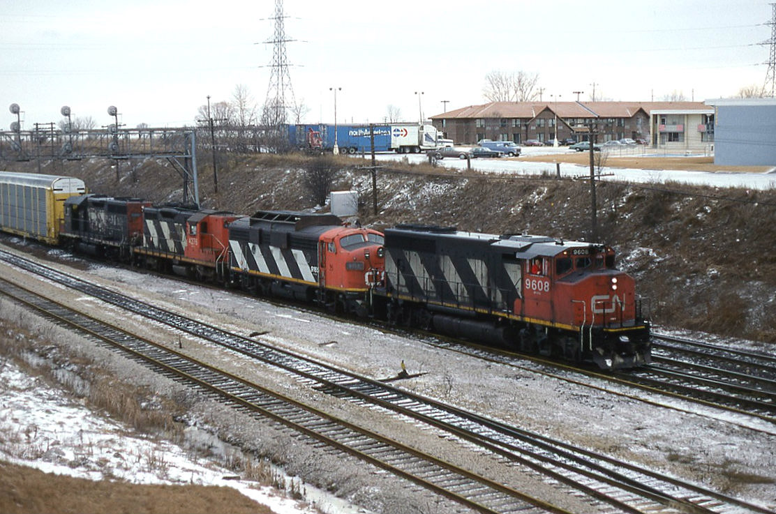 CN train 318. Always a prize catch in its day. On this dull over cast morning 318 would not let rail fans down.Switching its train at the east end of Oshawa yard a GP40-2W, A covered wagon all decked out for plow service, a GP9 with flexi coil trucks and a standard cab GP40 entering its last few months of service. Not to be past up.