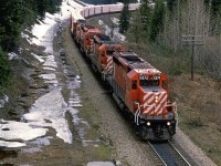 At the height of the Selkirk Mountains and Rogers Pass, this eastbound manifest is a couple kilometers from entering the Connaught Tunnel. The MacDonald Tunnel is under construction at this time.