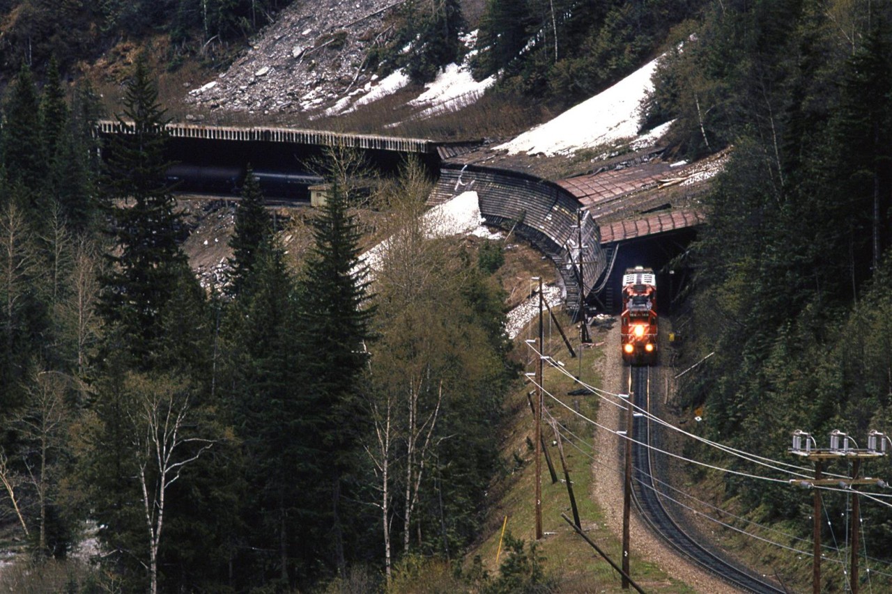 I have always been enamored with snow sheds - even more so than with tunnels. In deep dark Illecillewaet (I had to look that up) Canyon, there is a rather photogenic one. This westbound manifest dissipates heat from the locomotive's dynamic brake blisters as it reins in the 100 cars pushing on them.