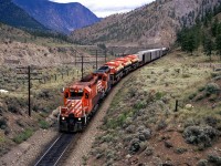 Westbound manifest about to pass under the Trans Canada Highway. The three leading flat cars have interesting tracked vehicles. 