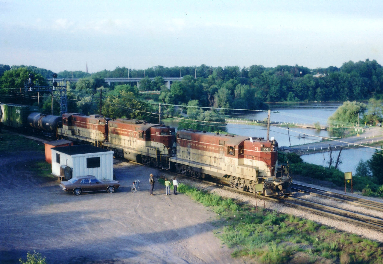 The TH&B Starlite on its' way toward Hamilton was down to a crawl due to a work gang clearing; and this gave the engineer a chance to make friends with a couple of young lads that were 'wowed' by enjoying a moving train up close. The older fella I did not know either; but this scene has a bit of human side to it that is not seen very often anymore in this age of "rushing to make a dollar"..  And worse, this once popular train watching spot for people of all ages is now off limits. Long shadows means it is past 7PM as TH&B 74, 402 and 75 make their way along on what looks to be a nice summers' eve.