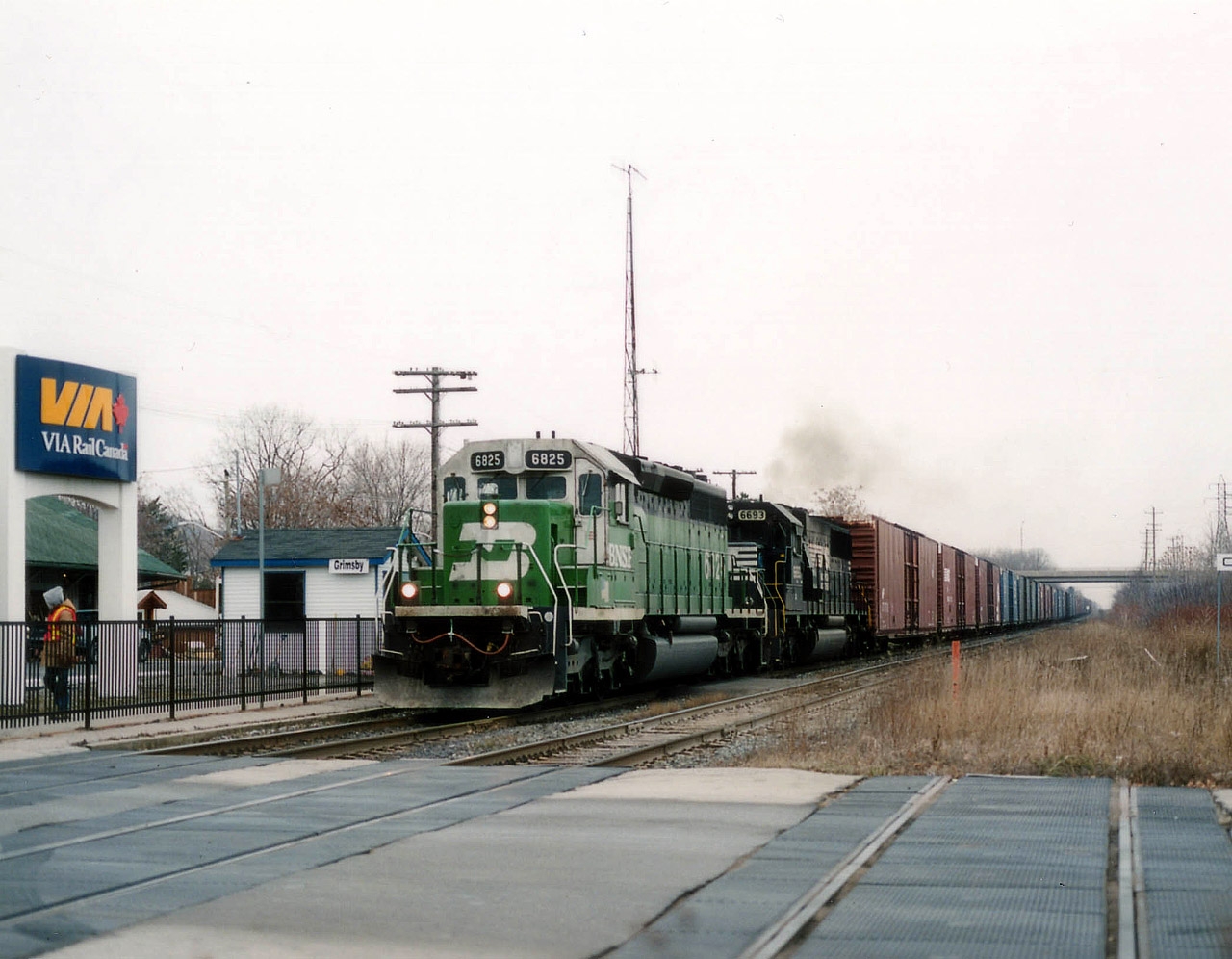 NS train #328 heading from St. Thomas (Talbotville) to Buffalo, autoparts, daily, always had a surprise in its' power consist. Or so it seemed. Here's one of my favourite schemes, that white & green faced BNSF leading a NS 6693 as it roars past the town VIA kiosk. Considerable expense went into setting up the new kiosk and a fancy sign; and of course what does VIA do? Cancel all operations down Niagara-way. Worse, the #328 is now history too. Getting quiet in ol' Grimsby-town. :o(